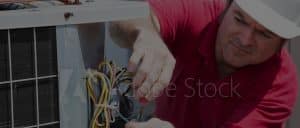 Stock photo of HVAC tech wiring outdoor unit.
